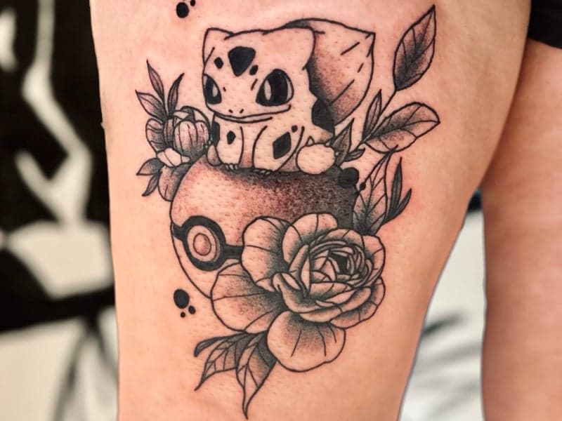 Zwart-wit tattoo van Bulbasaur op een Pokéball met bloemen.