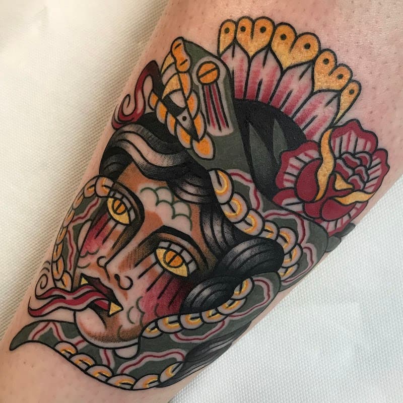 Traditionele tattoo van een vrouwenhoofd met slang en roos.