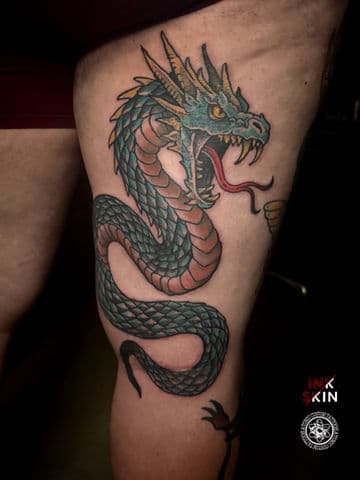 Kleurrijke traditionele draak tattoo op bovenbeen.