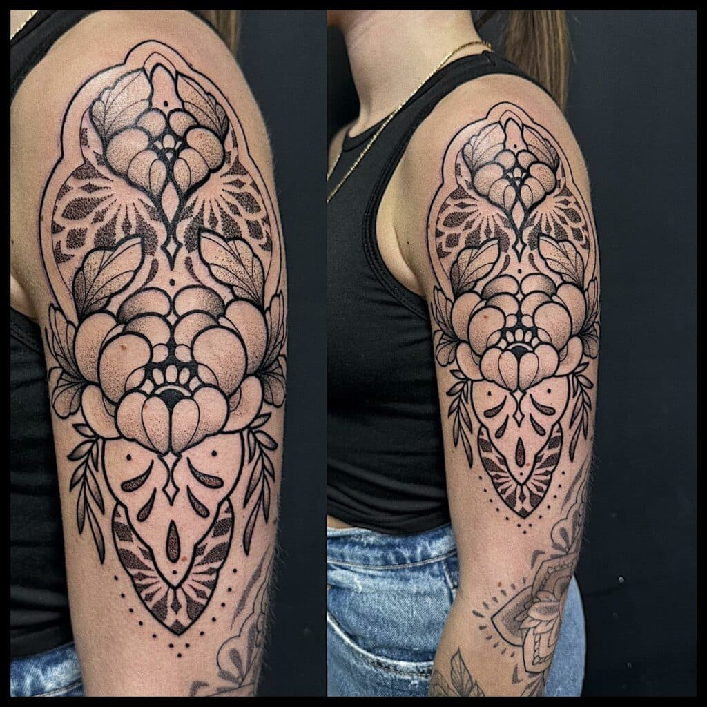 Grote ornamentale bloemen tattoo met dotwork op bovenarm.