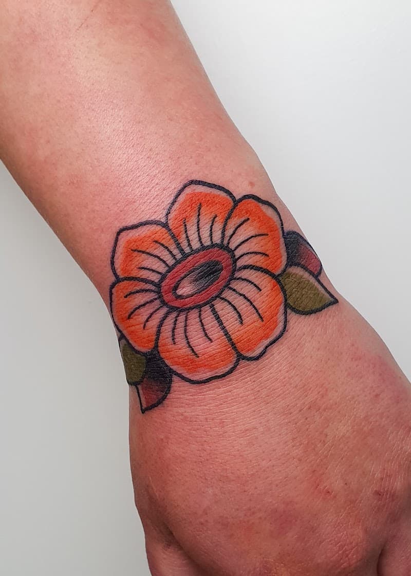 Traditionele oranje bloem tattoo op de pols.