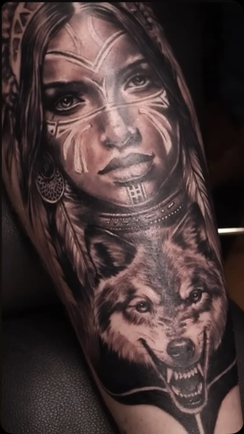 Realistisch portret van inheemse vrouw met wolf op bovenarm.