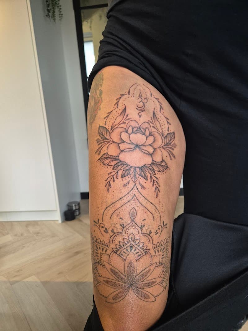 Grote ornamentale tattoo met bloem en mandala op bovenbeen.