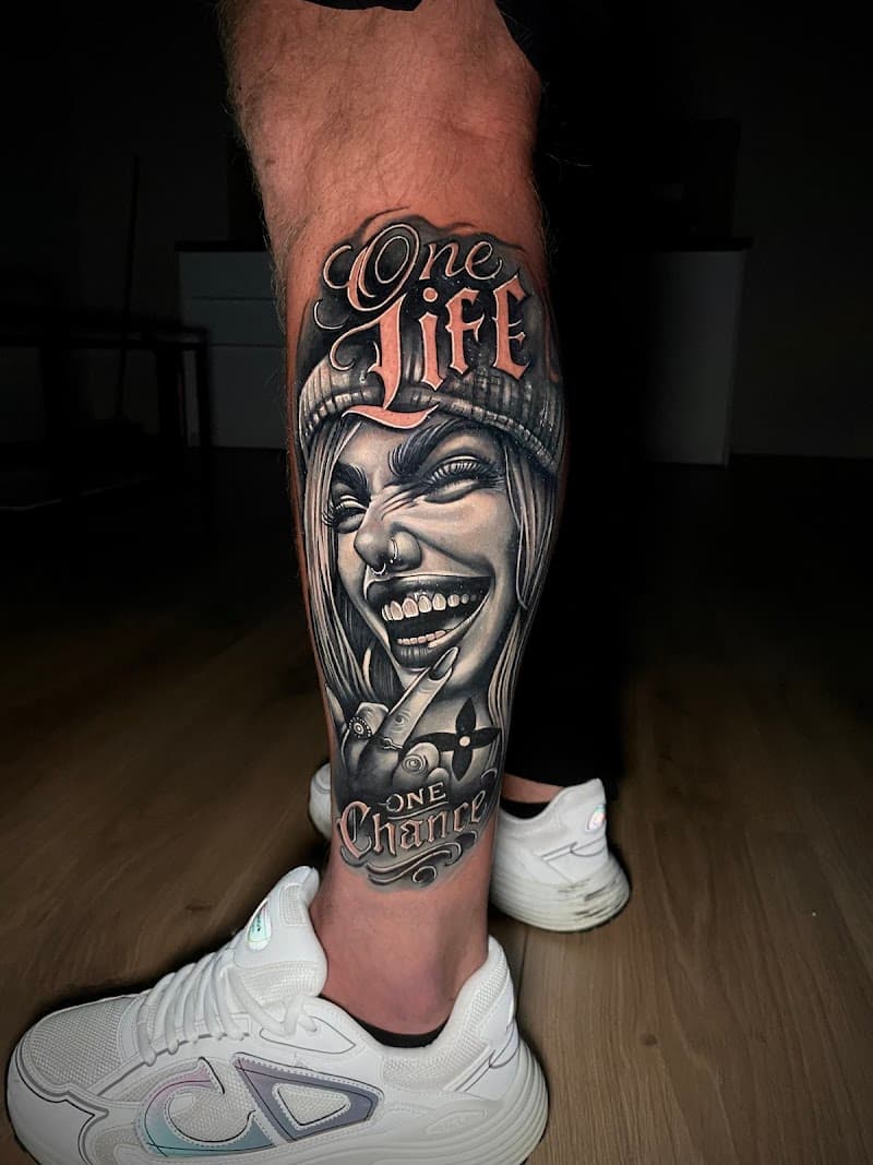 Black & grey tattoo van een lachende vrouw met muts en tekst 'One Life One Chance'.