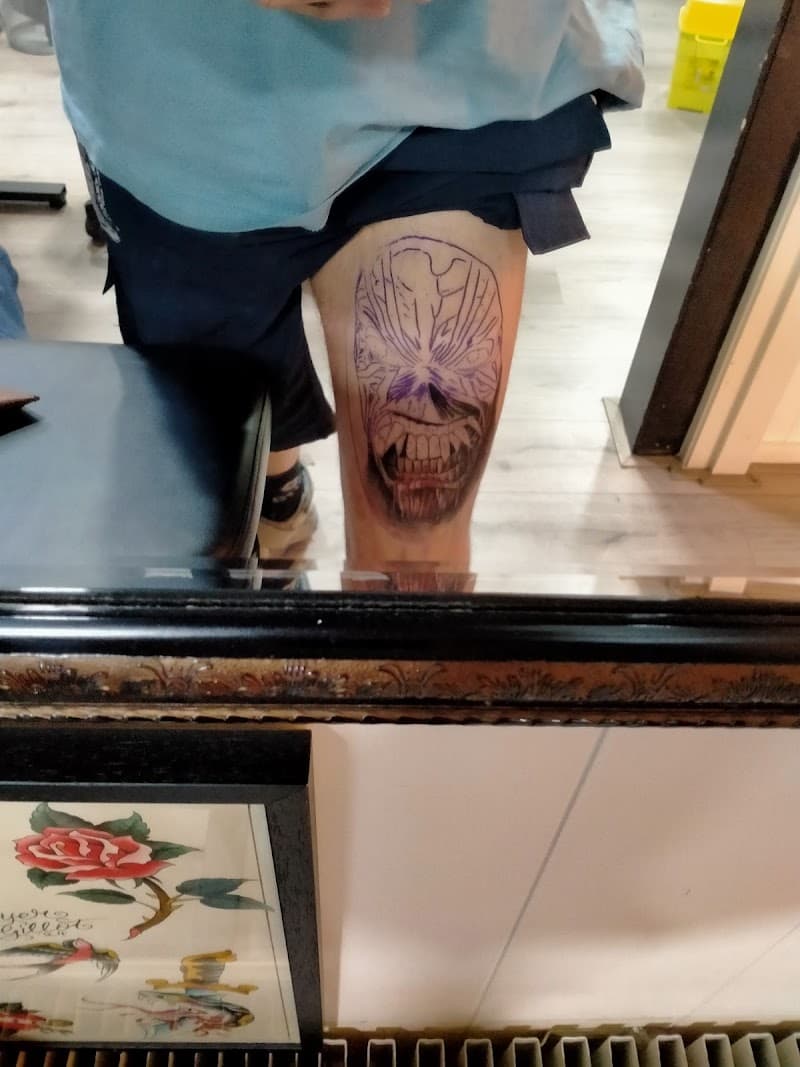 Grote, deels ingekleurde schedel/monster tattoo op bovenbeen.