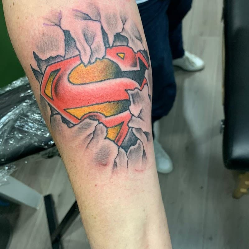 Superman logo dat door de huid breekt op het onderbeen.