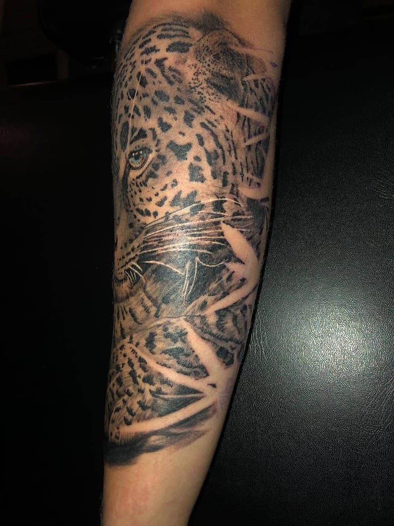 Realistische luipaard kop met felblauw oog op onderarm.