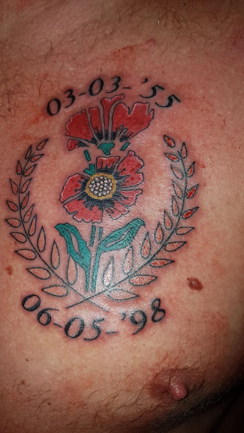 Rode klaproos met lauwerkrans en datums 03-03-'55 en 06-05-'98 op de borst.