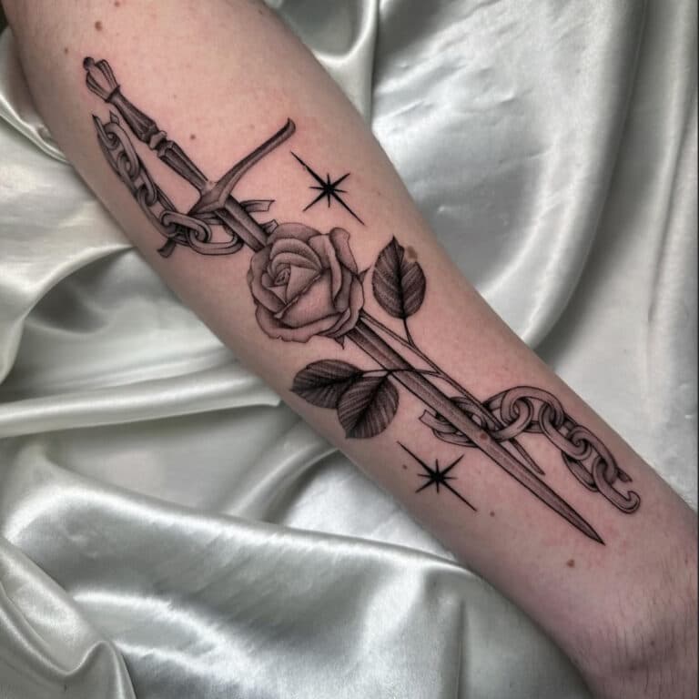 Illustratieve tattoo van een zwaard door een roos met ketting op de onderarm.