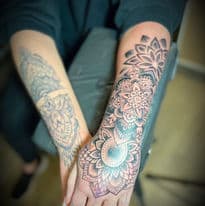 Grote mandala tattoo op onderarm en hand, met een oudere tattoo op de andere arm.