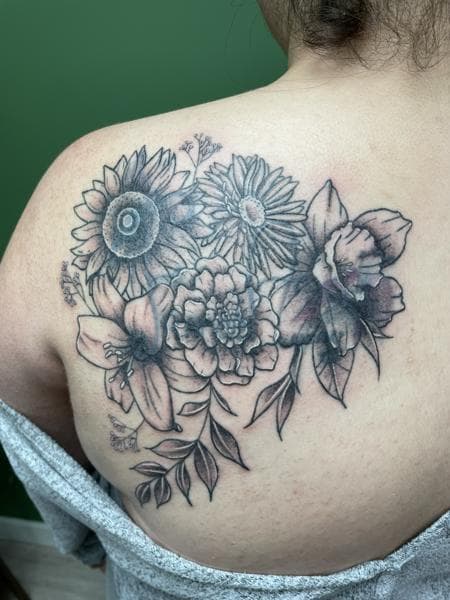 Zwart-wit bloemenboeket met zonnebloem, lelie en narcis op schouderblad.