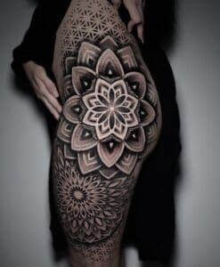 Grote geometrische mandala tattoo op bovenbeen en heup.