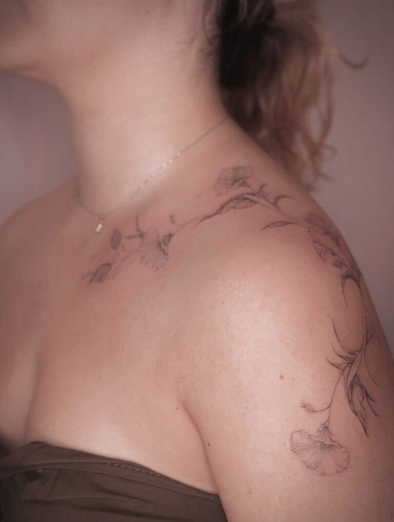 Fineline bloementattoo op schouder en bovenarm.