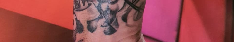 Zwart-wit tattoo van een schedel en bloemen op de pols.