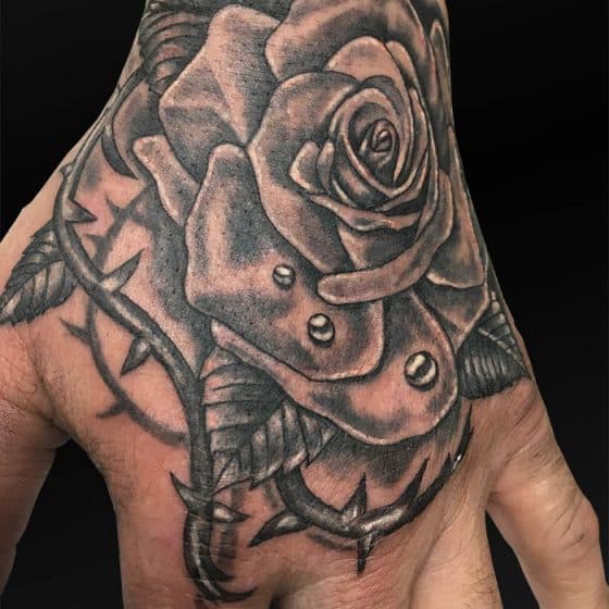 Zwart-wit roos met doornen en waterdruppels op hand.