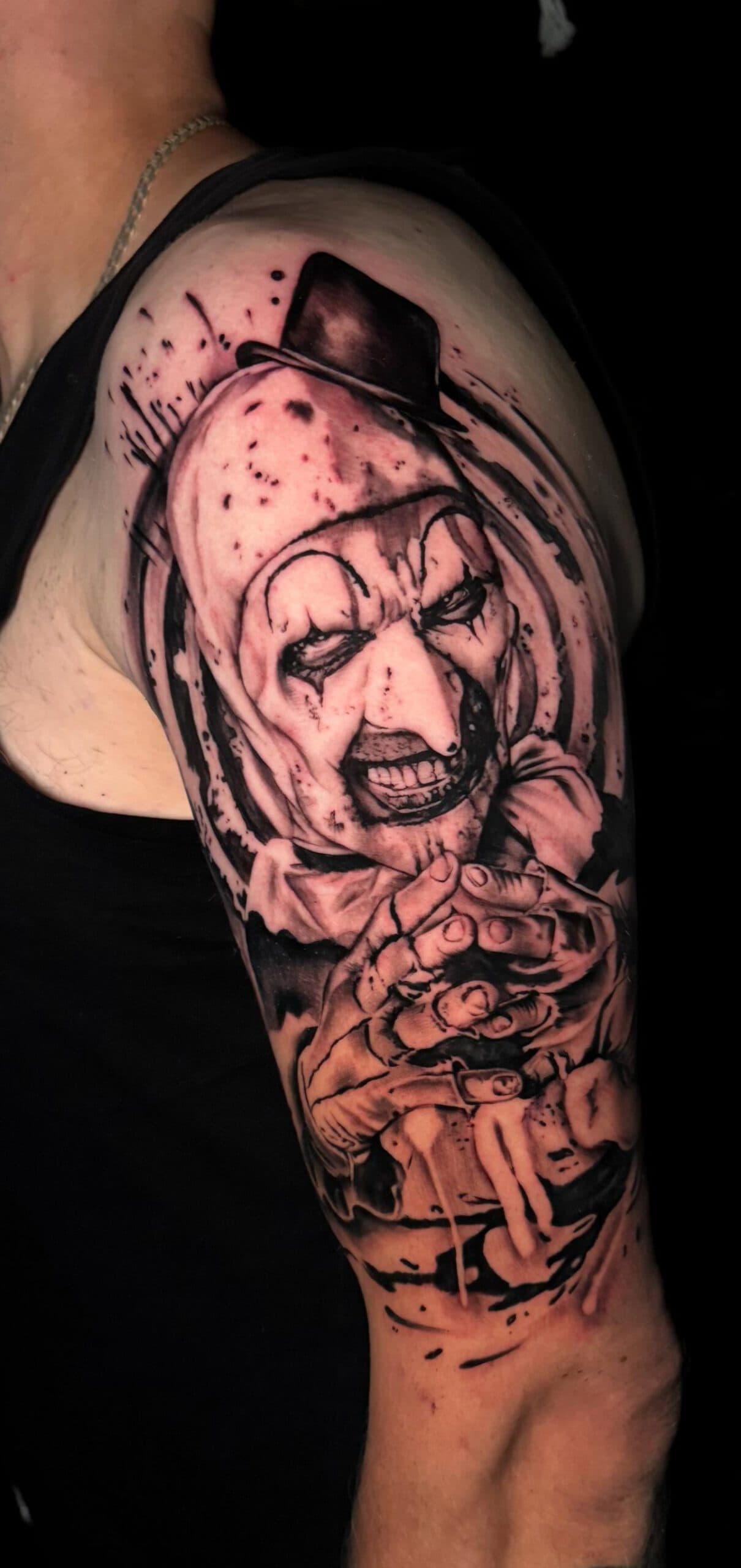 Blackwork tattoo van Art the Clown uit Terrifier op de bovenarm.