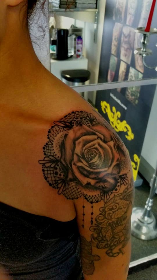 Zwart-wit roos met kanten patroon op schouder.