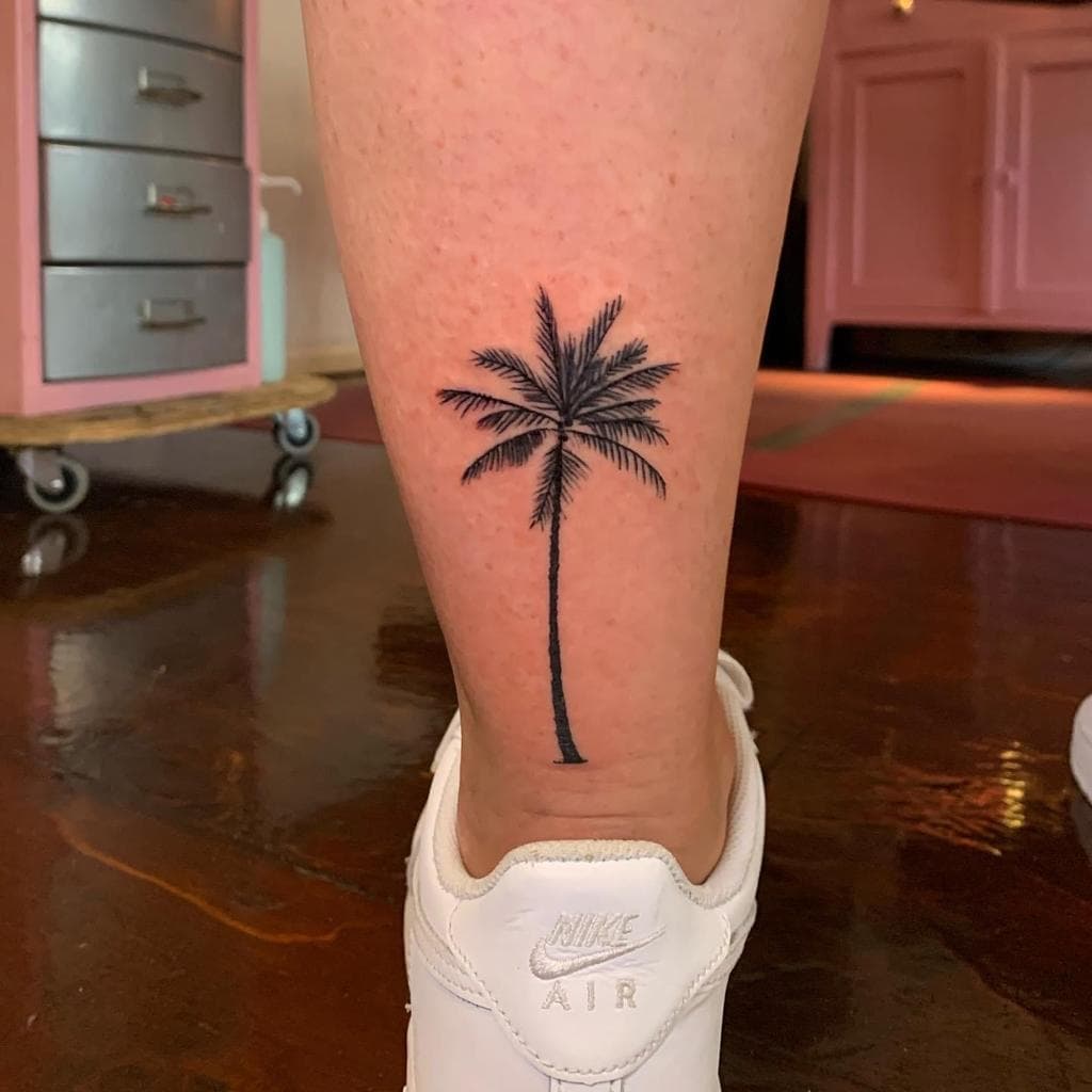 Zwarte palmboom tattoo op het onderbeen.