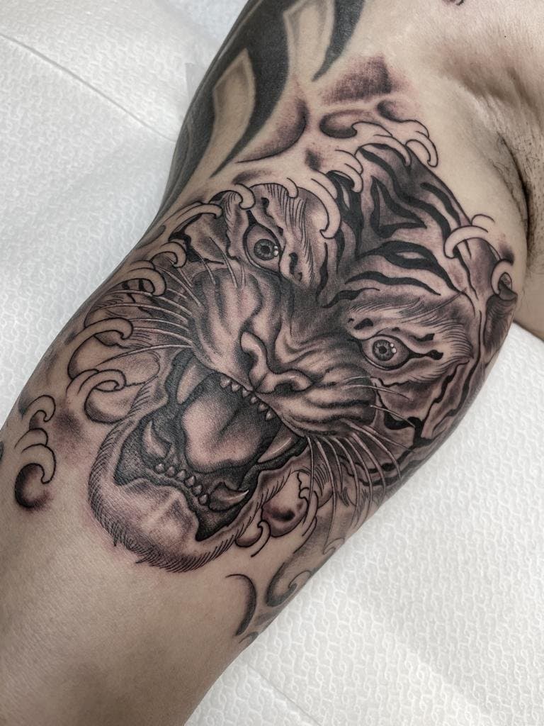 Zwart-wit tijgerkop met Japanse golven op de bovenarm.