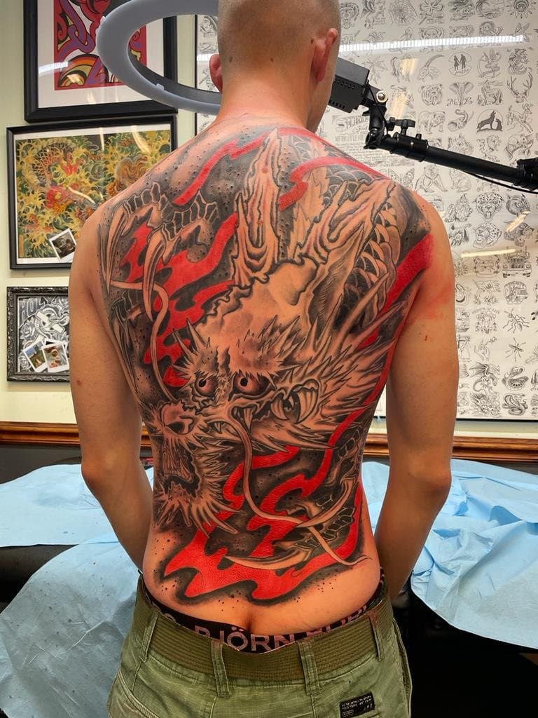 Grote Japanse draak tattoo op de volledige rug, zwart-grijs met rode accenten.