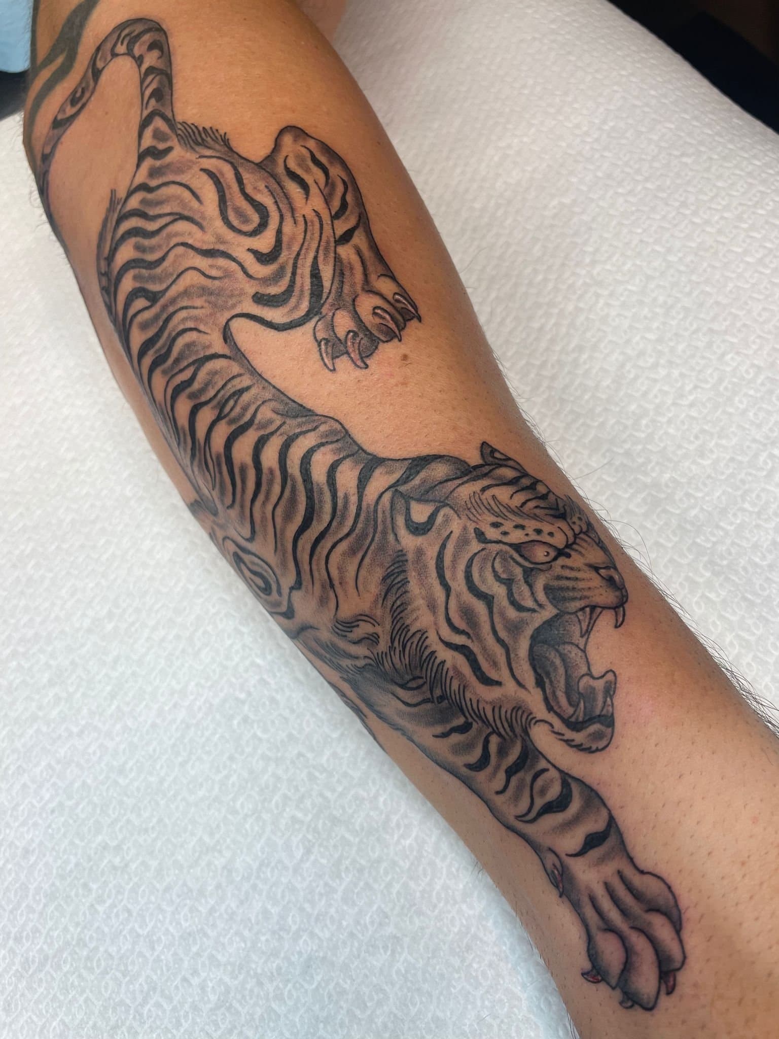 Zwart-grijze Japanse tijger tattoo op onderbeen.