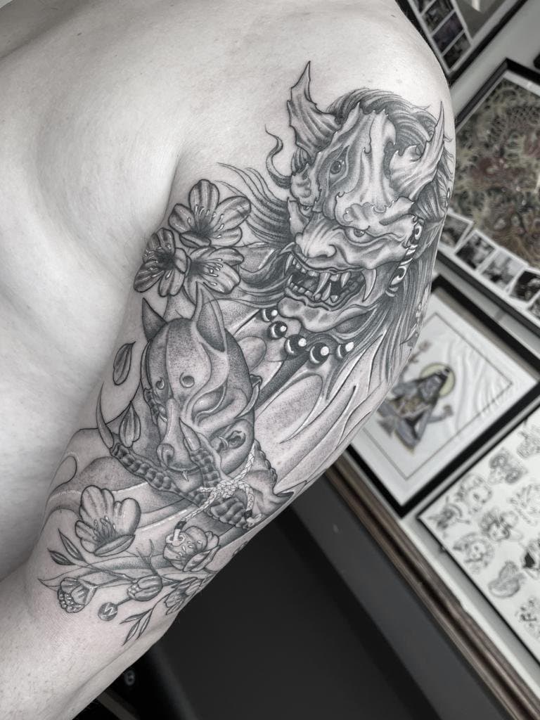 Zwart-wit Hannya masker en kitsune masker met bloesem op bovenarm.