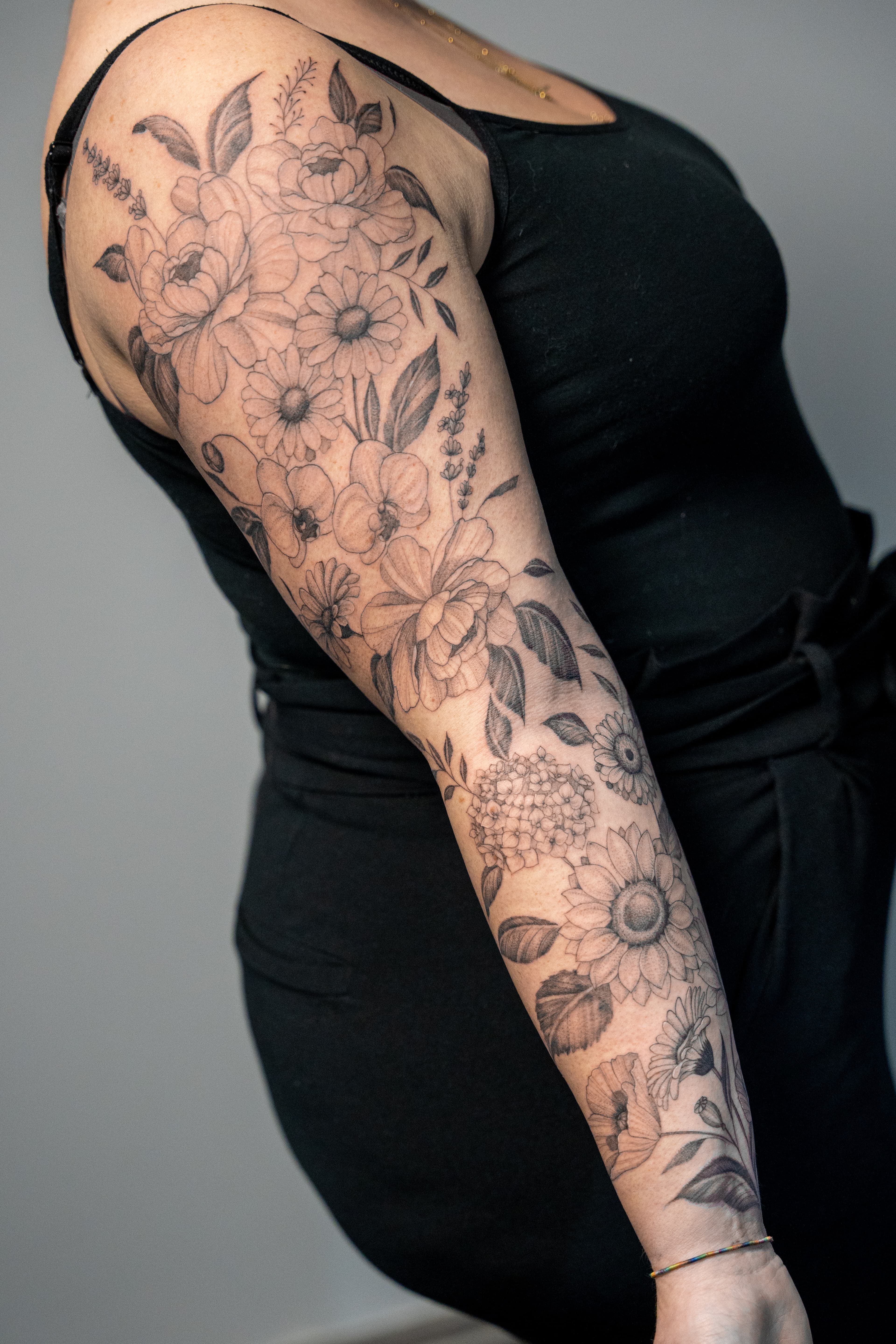 Gedetailleerde fineline bloemen sleeve op arm.