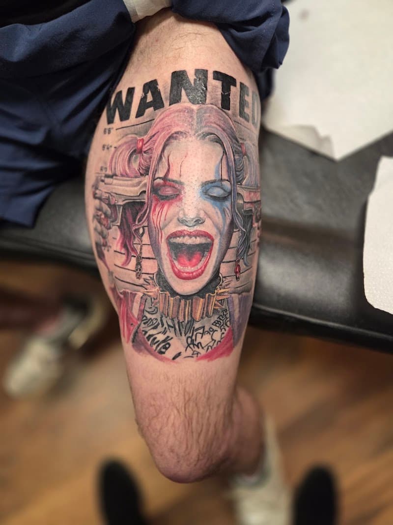 Realistische Harley Quinn 'WANTED' tattoo op bovenbeen.
