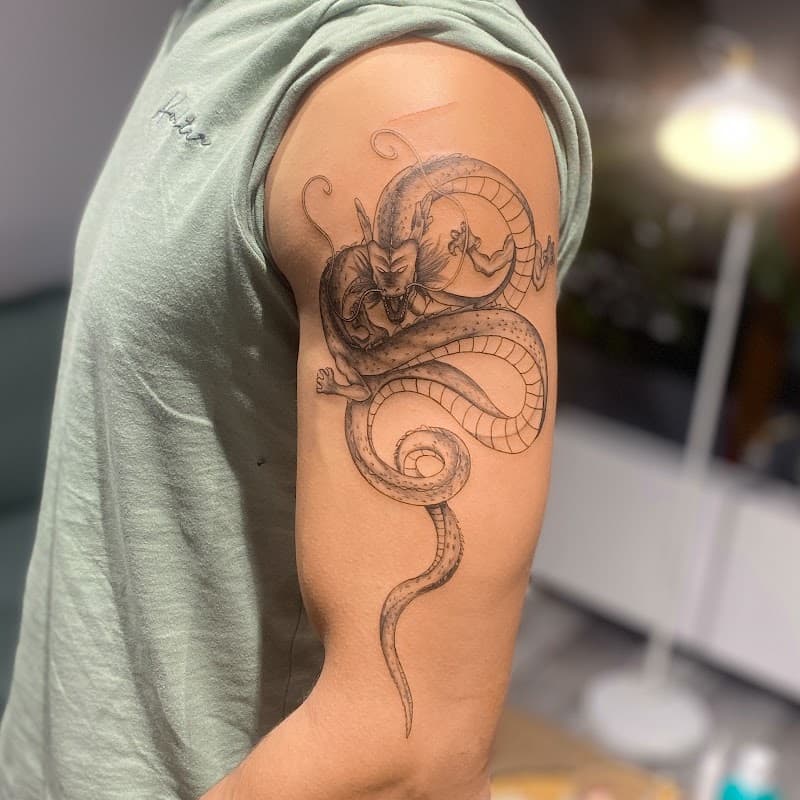 Gedetailleerde fineline draak tattoo op de bovenarm.