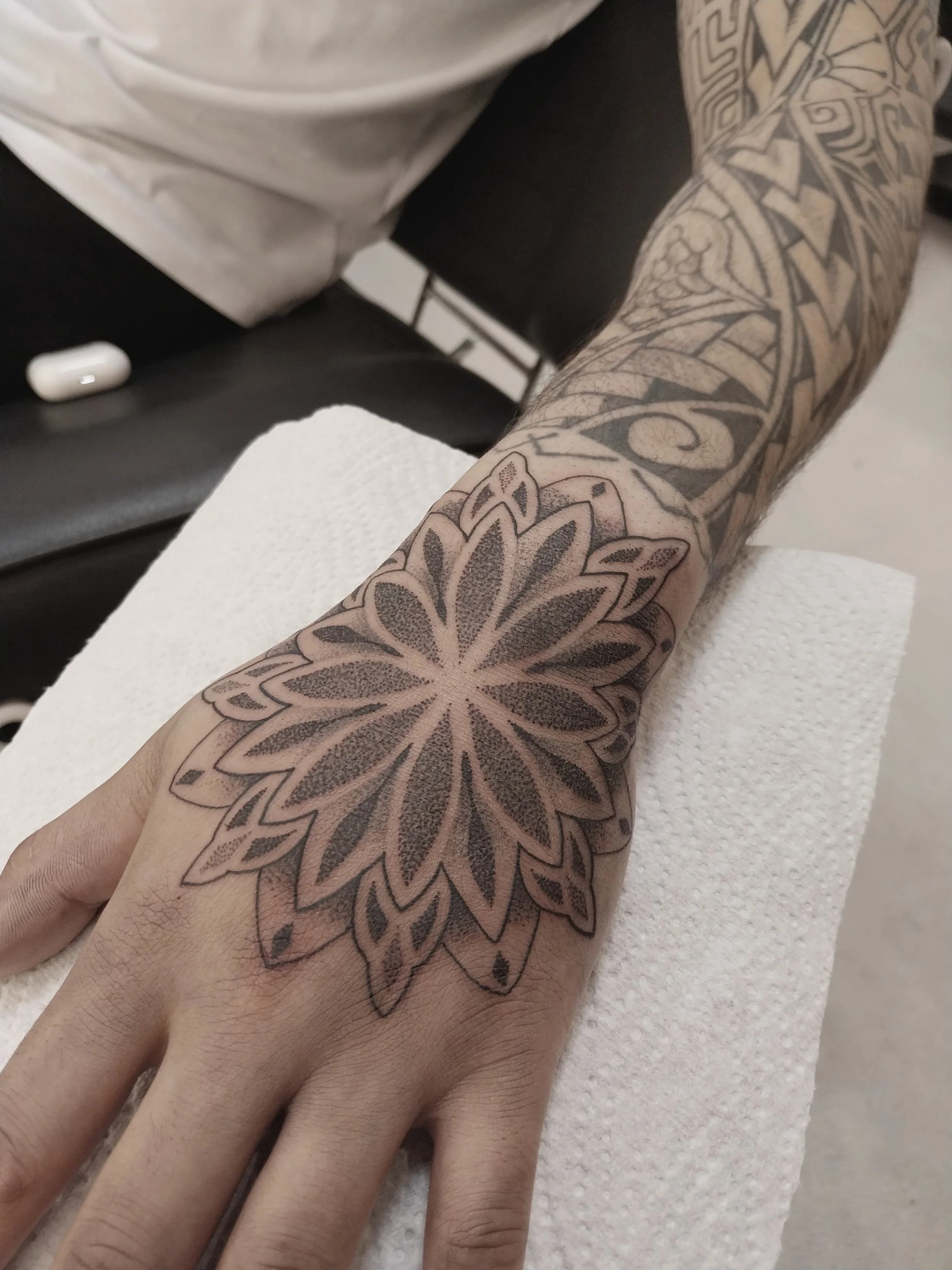 Grote dotwork mandala tattoo op de bovenkant van de hand.