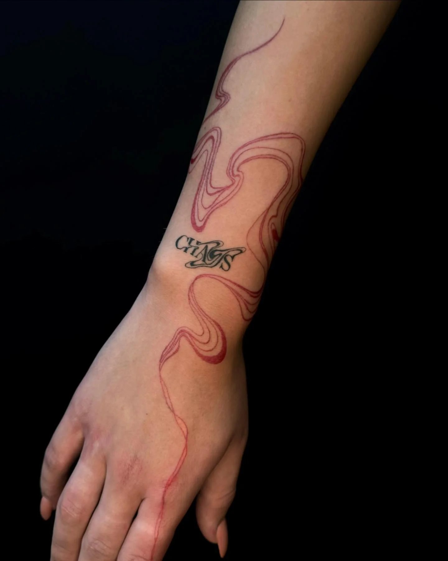 Rode golvende lijnen en zwarte 'CHAOS' tekst op pols en hand.