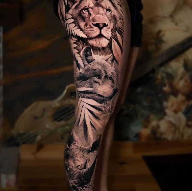 Realistische tattoo van leeuw, wolf en neushoorn op been.