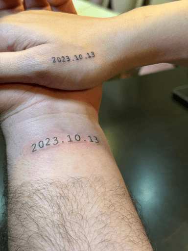 Twee minimalistische datum tattoos '2023.10.13' op polsen.