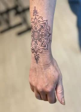 Gedetailleerde mandala tattoo op de pols en onderarm.