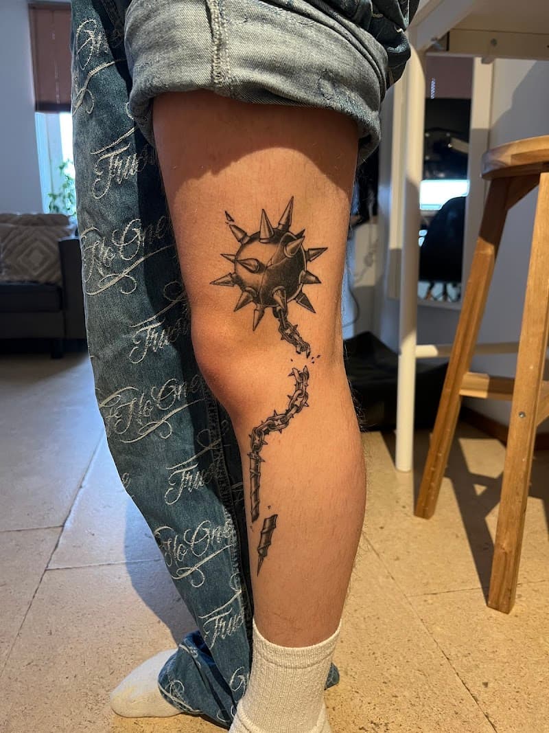Blackwork tattoo van een morgenster met gebroken ketting op het onderbeen.