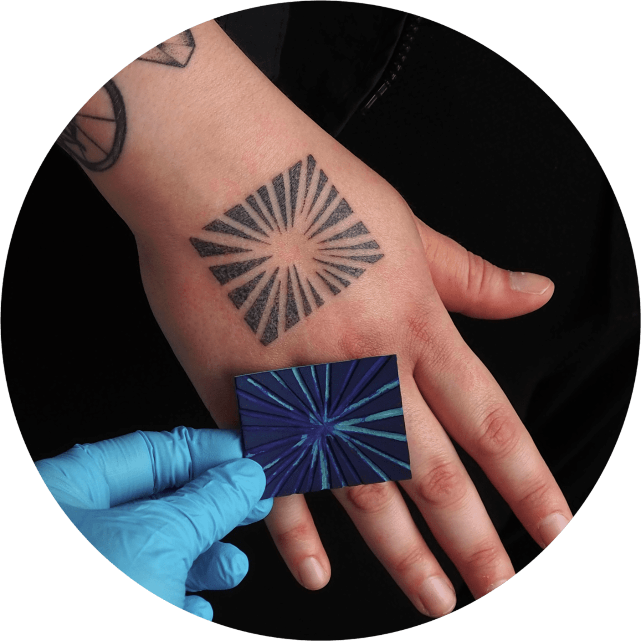 Geometrische zonnestraal tattoo op de hand, met referentiekaart.