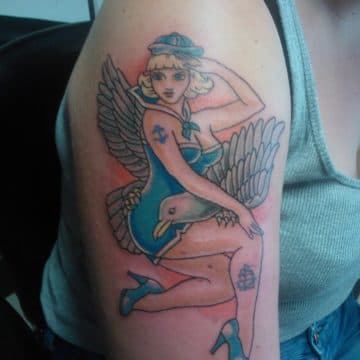 Kleurrijke traditionele pin-up girl met vleugels op bovenarm.