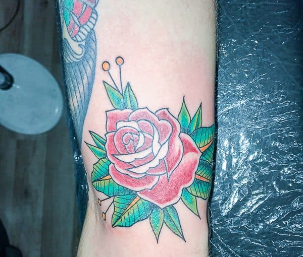 Traditionele roos tattoo in kleur op de arm.
